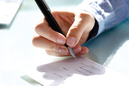 Photo for Close-up Of A Businesswoman's Hand Signing Cheque - Royalty Free Image