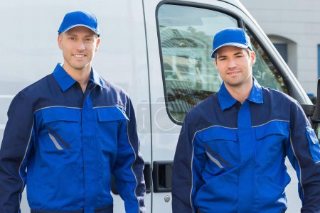 Téléchargez les photos : Portrait complet de techniciens confiants debout contre camion sur la rue - en image libre de droit
