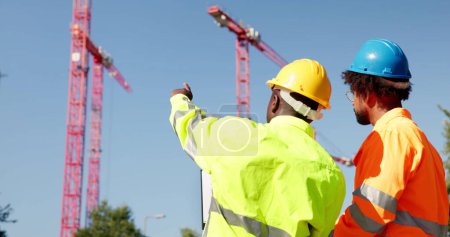 Téléchargez les photos : Construire Site Engineer Pointing. Inspecteur des travailleurs avec presse-papiers - en image libre de droit