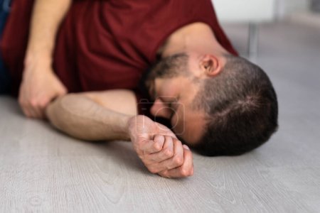 Foto de Hombre inconsciente acostado en el suelo en un accidente provocado por epilepsia en la habitación - Imagen libre de derechos