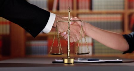 Photo for Close-up Of A Justice Scale With Judge And Client Shaking Hands In A Courtroom - Royalty Free Image