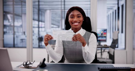 Téléchargez les photos : Femme d'affaires tient le chéquier, examinant le chèque de paie et le chèque - en image libre de droit
