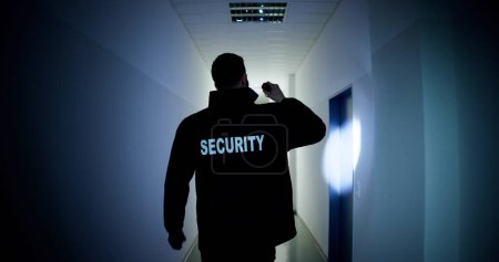 Téléchargez les photos : Homme garde de sécurité tenant lampe de poche debout dans le couloir du bâtiment - en image libre de droit