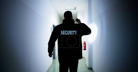 Foto de Guardia de seguridad masculino sosteniendo linterna de pie en el pasillo del edificio - Imagen libre de derechos