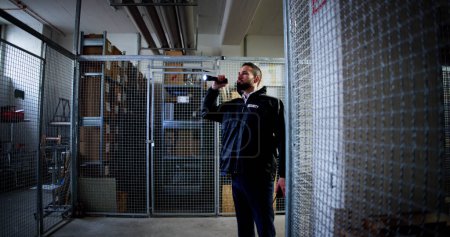 Téléchargez les photos : Gardien de sécurité dans l'entrepôt tenant une lampe de poche - en image libre de droit
