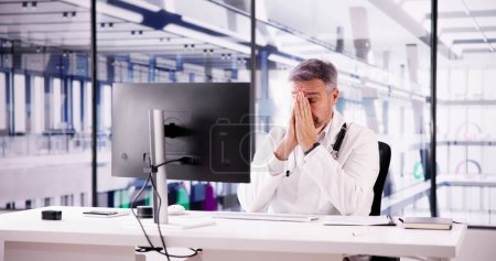 Foto de Triste hombre médico estrés y dolor en la computadora - Imagen libre de derechos