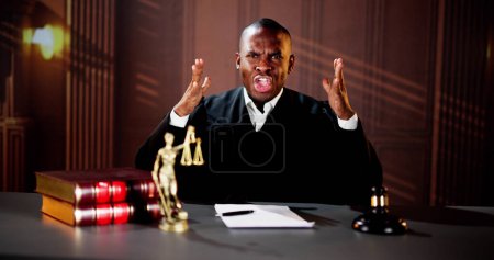 Photo for Angry Judge Talking In Courtroom At Table - Royalty Free Image