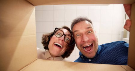 Photo for Low Section View Of A Young Happy Couple Looking Inside Cardboard Box - Royalty Free Image