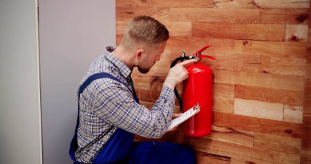 Foto de Primer plano de Hombre Comprobación Profesional Un extintor de incendios - Imagen libre de derechos