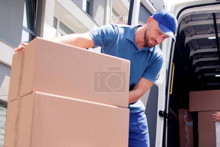 Téléchargez les photos : Courriers et déménageurs transportent rapidement les boîtes par camion - en image libre de droit