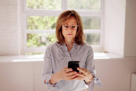 Foto de Mensajes de texto en el teléfono inteligente o celular en la oficina - Imagen libre de derechos