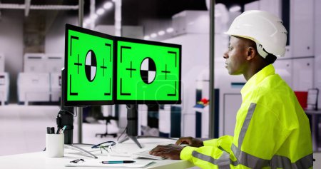Téléchargez les photos : Ingénieur utilisant le moniteur de PC avec l'écran vert dans l'usine moderne - en image libre de droit