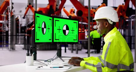 Foto de Ingeniero que utiliza el monitor de la PC con la pantalla verde en fábrica moderna del coche - Imagen libre de derechos