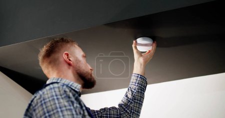 Téléchargez les photos : Installation du détecteur de fumée sur le plafond à la maison - en image libre de droit