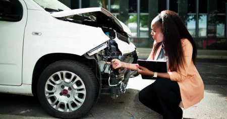 Téléchargez les photos : Agent d'assurance automobile afro-américain inspectant la réclamation d'accident - en image libre de droit