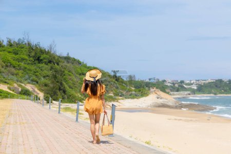Téléchargez les photos : Voyage femme avec chapeau de paille et marcher le long de la plage de sable - en image libre de droit