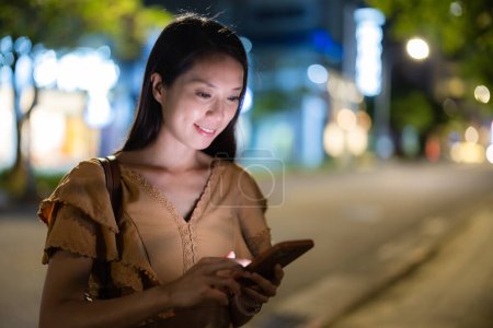 Foto de Mujer asiática uso de teléfono inteligente en la ciudad por la noche - Imagen libre de derechos