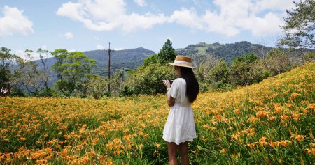 Foto de Mujer tomar una foto en el campo de flores Daylily en Taimali Kinchen Mountain en Taitung de Taiwán - Imagen libre de derechos