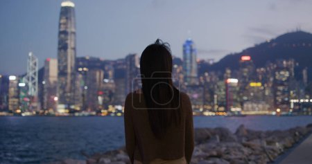Téléchargez les photos : Femme regarder la vue sur le paysage de la ville la nuit - en image libre de droit