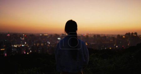Téléchargez les photos : Silhouette de femme regarder la ville sous le coucher du soleil - en image libre de droit