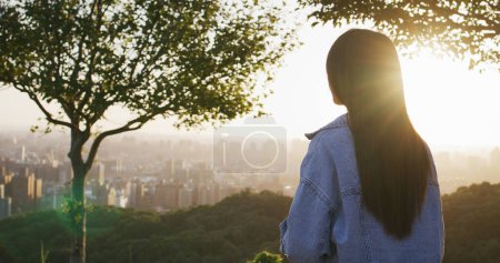 Téléchargez les photos : Femme regarder la vue sur la ville sous le coucher du soleil - en image libre de droit