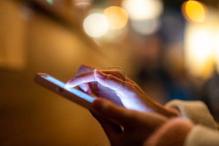 Téléchargez les photos : Femme utiliser le téléphone portable au restaurant la nuit - en image libre de droit