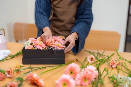Téléchargez les photos : Fleuriste femelle faire une boîte de fleur dans l'espace de travail - en image libre de droit