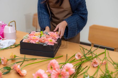 Foto de Floristería femenina hacer una caja de flores en el espacio de trabajo - Imagen libre de derechos
