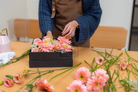 Téléchargez les photos : Fleuriste femelle faire une boîte de fleur dans l'espace de travail - en image libre de droit