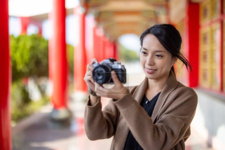 Téléchargez les photos : Voyage femme utiliser un appareil photo numérique pour prendre des photos dans le temple chinois - en image libre de droit