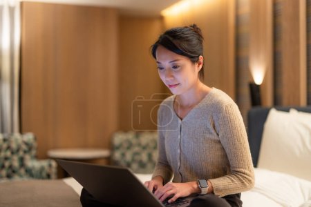 Foto de Mujer trabajar en el ordenador portátil y sentarse en la cama por la noche - Imagen libre de derechos