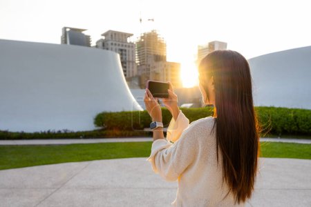 Photo for Woman use cellphone to take photo with sunlight flare under sunset - Royalty Free Image