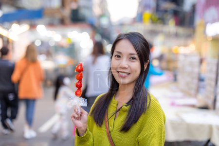 Photo for Woman hold with Tanghulu traditional Chinese hard caramel coated strawberry skewer at street market - Royalty Free Image