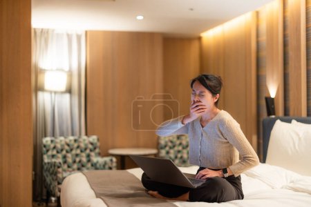 Foto de Mujer se siente cansado por el uso de la computadora portátil tanto tiempo en la cama - Imagen libre de derechos