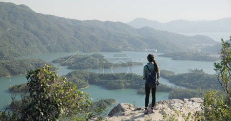 Woman go hiking and stand at the top of mountain