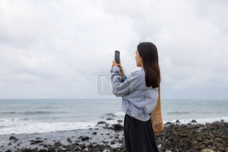 Téléchargez les photos : Femme prendre des photos sur téléphone portable sur la mer - en image libre de droit