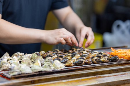 Téléchargez les photos : Griller l'huître et la palourde sur un filet métallique dans le marché de rue - en image libre de droit