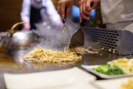 Téléchargez les photos : Chef Teppanyaki préparant la nourriture sur une plaque métallique chaude - en image libre de droit