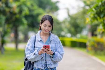 Foto de Mujer asiática utilizar el teléfono inteligente en el parque - Imagen libre de derechos