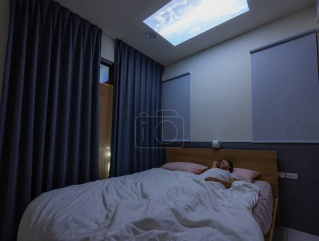 Téléchargez les photos : Femme couchée sur le lit et regarder le projet vidéo sur le plafond à la maison - en image libre de droit