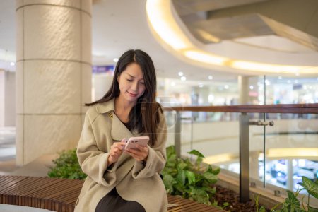 Photo for Woman use smart phone and sit inside shopping mall - Royalty Free Image