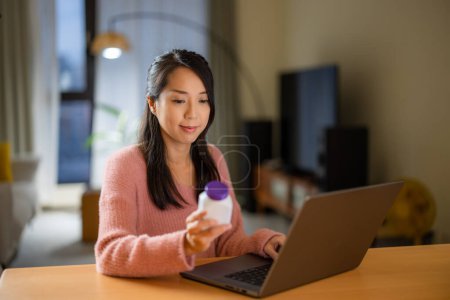 Photo for Woman use laptop computer to check the medicine at home - Royalty Free Image