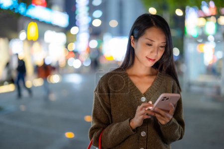 Téléchargez les photos : Femme utilisation du téléphone intelligent dans la ville la nuit - en image libre de droit