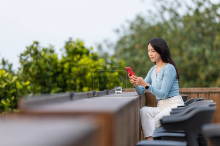 Foto de Mujer leer en el teléfono celular y sentarse fuera de la cafetería - Imagen libre de derechos