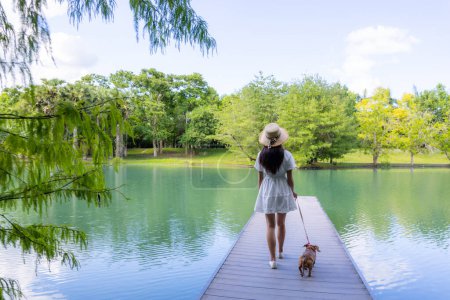 Foto de Mujer con su perro y caminar en la cubierta sobre la vista del estanque de agua - Imagen libre de derechos