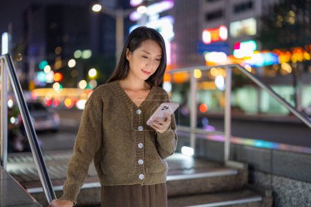Photo for Woman use of smart phone in city at night - Royalty Free Image