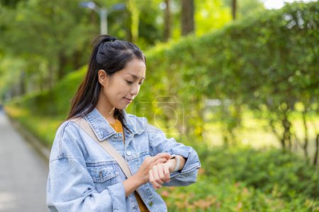 Téléchargez les photos : Femme utiliser montre intelligente au parc - en image libre de droit
