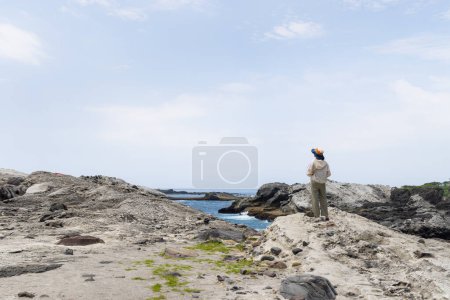 Téléchargez les photos : Femme debout sur le rocher et vue sur la plage - en image libre de droit