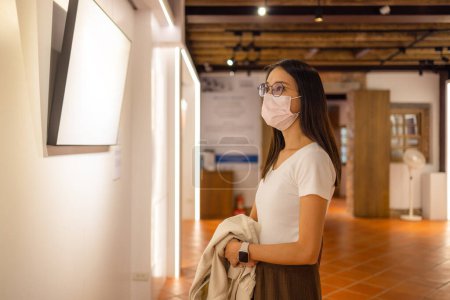 Téléchargez les photos : Femme porter masque facial dans le hall d'exposition d'art - en image libre de droit
