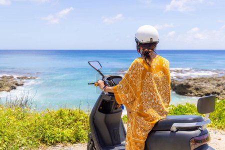 Téléchargez les photos : Femme en moto au bord de la mer, concept de road trip - en image libre de droit